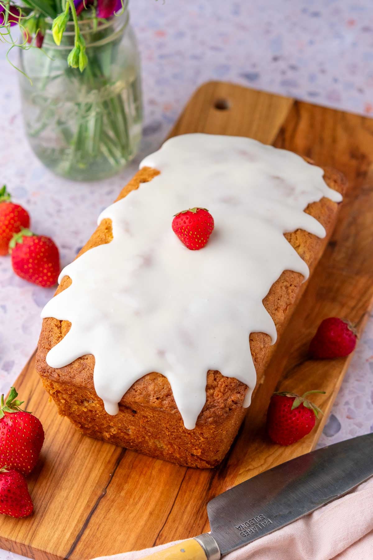 Sourdough Strawberry Bread with vanilla glaze on a cutting board.