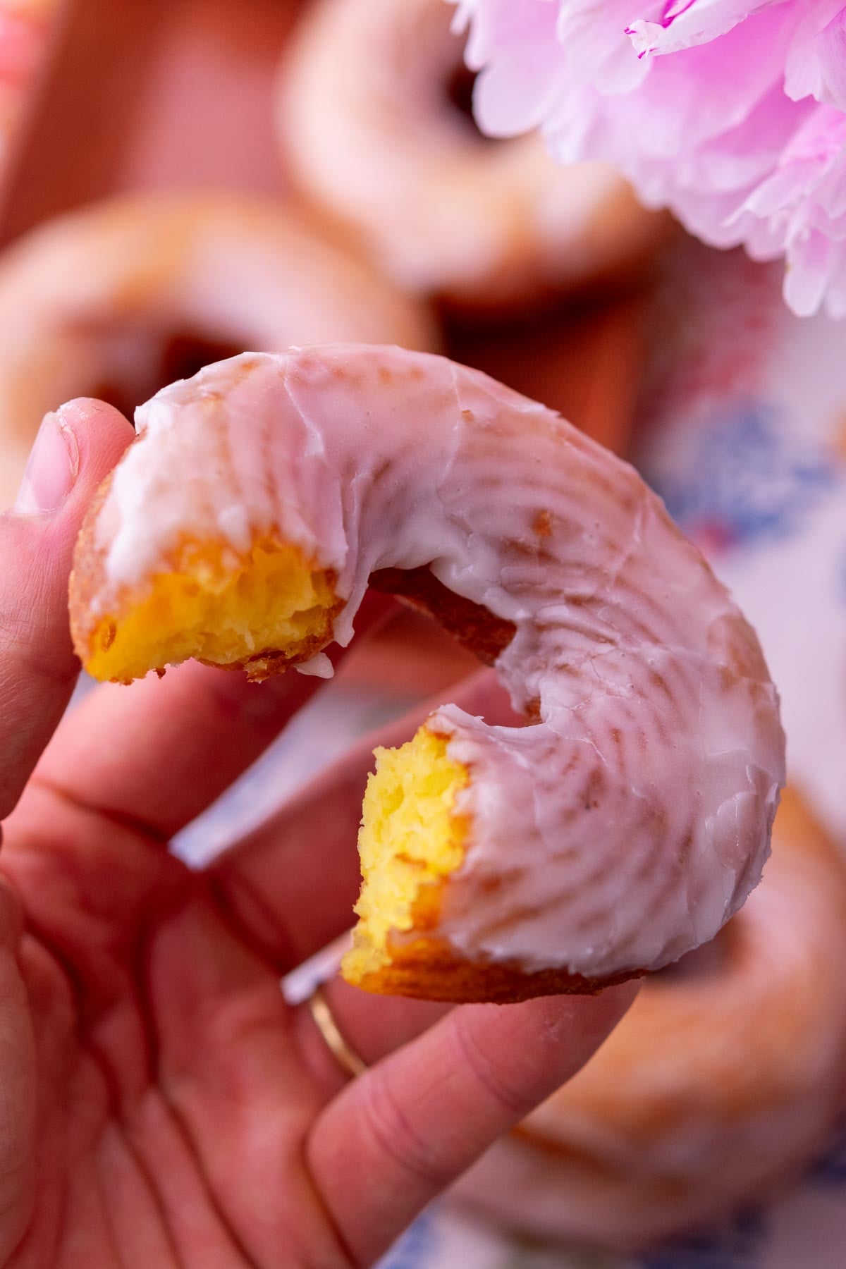 Hand holding a sourdough cruller with a bite taken out of it.