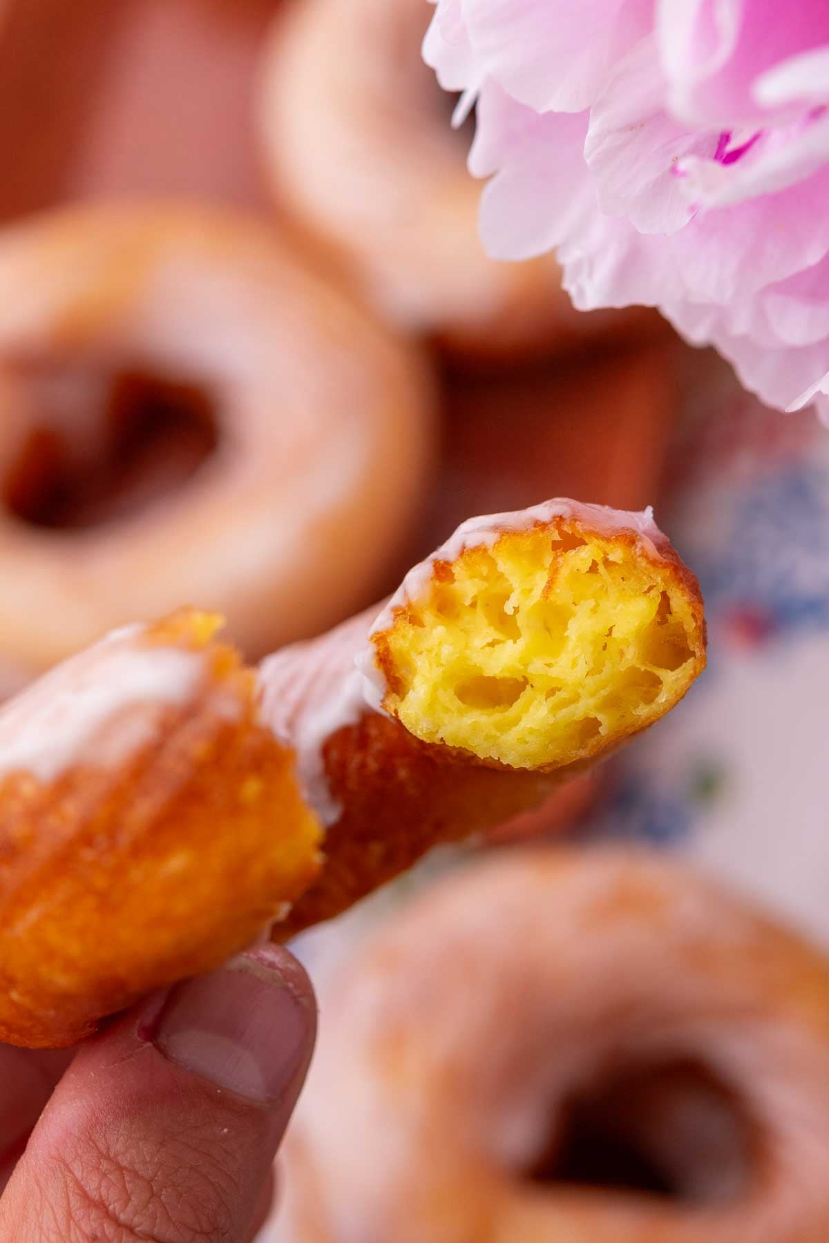 Hand holding a custardy and eggy interior of a bite of a sourdough cruller.