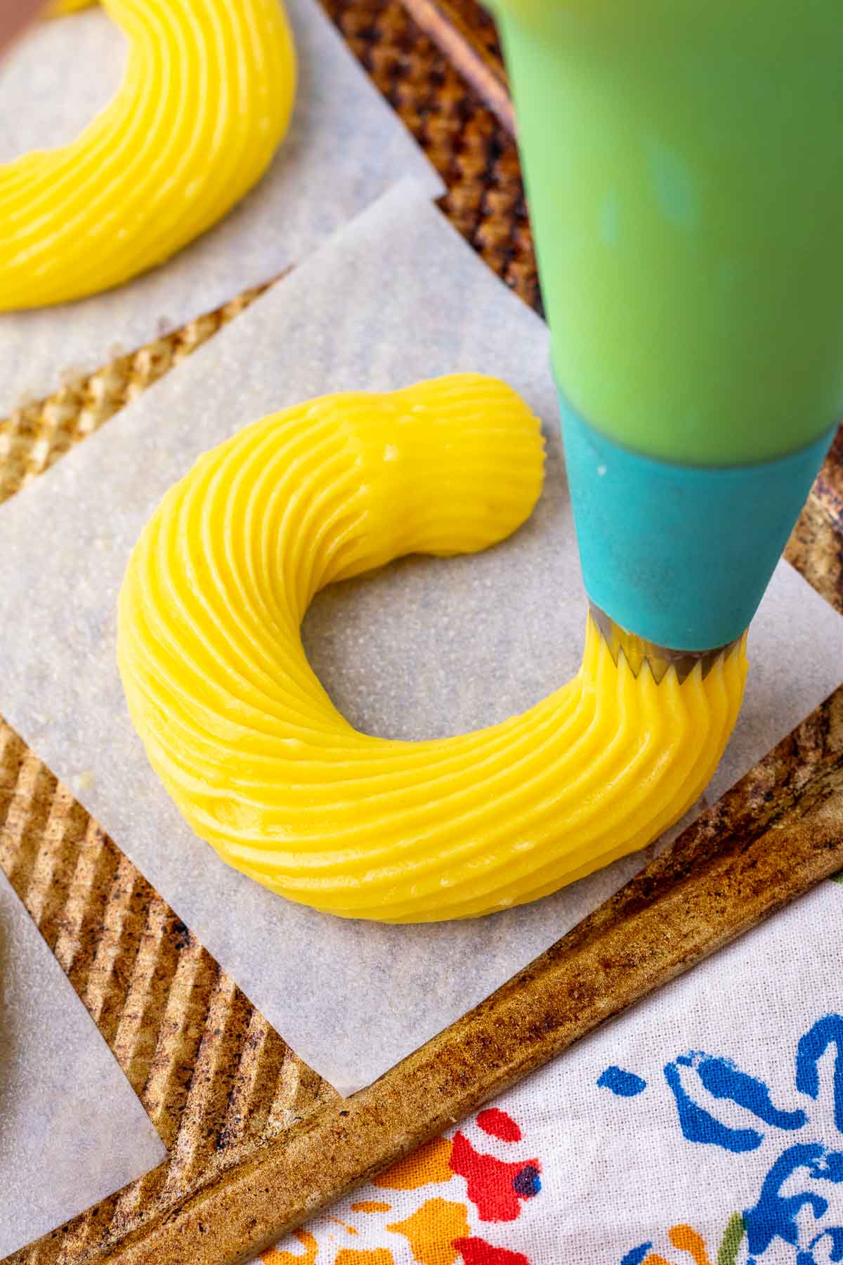 Piping a sourdough cruller on parchment paper with a large star tip.