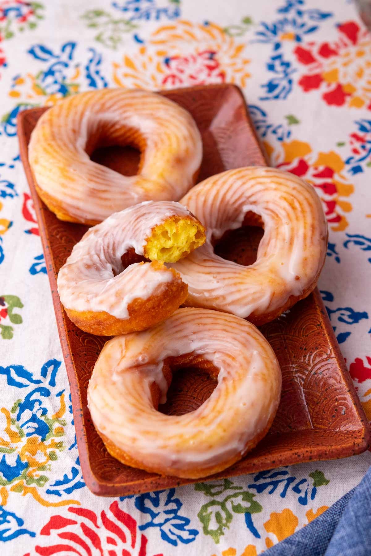 Plate of sourdough crullers with vanilla glaze and a bite taken out of one.