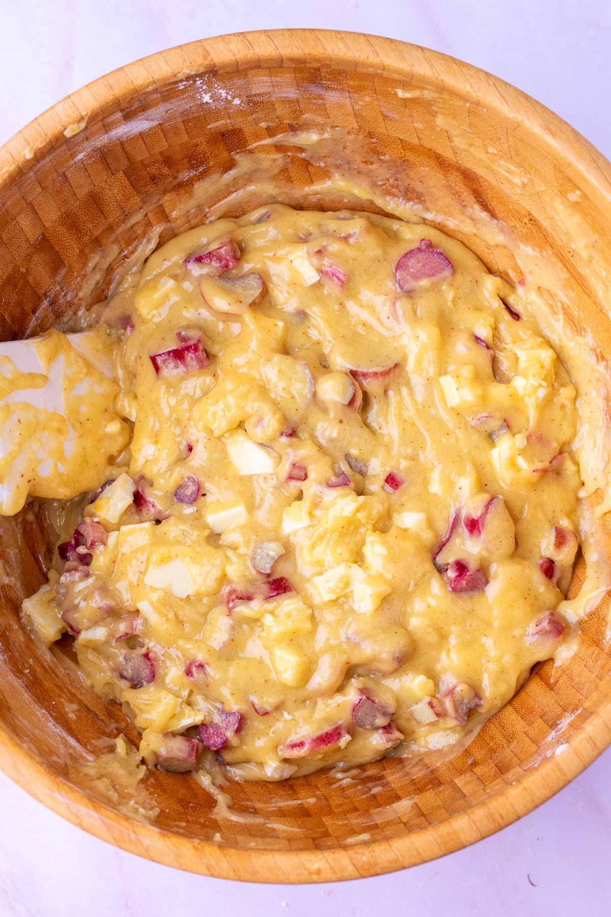 Wooden bowl of sourdough rhubarb cookie dough with a spatula.