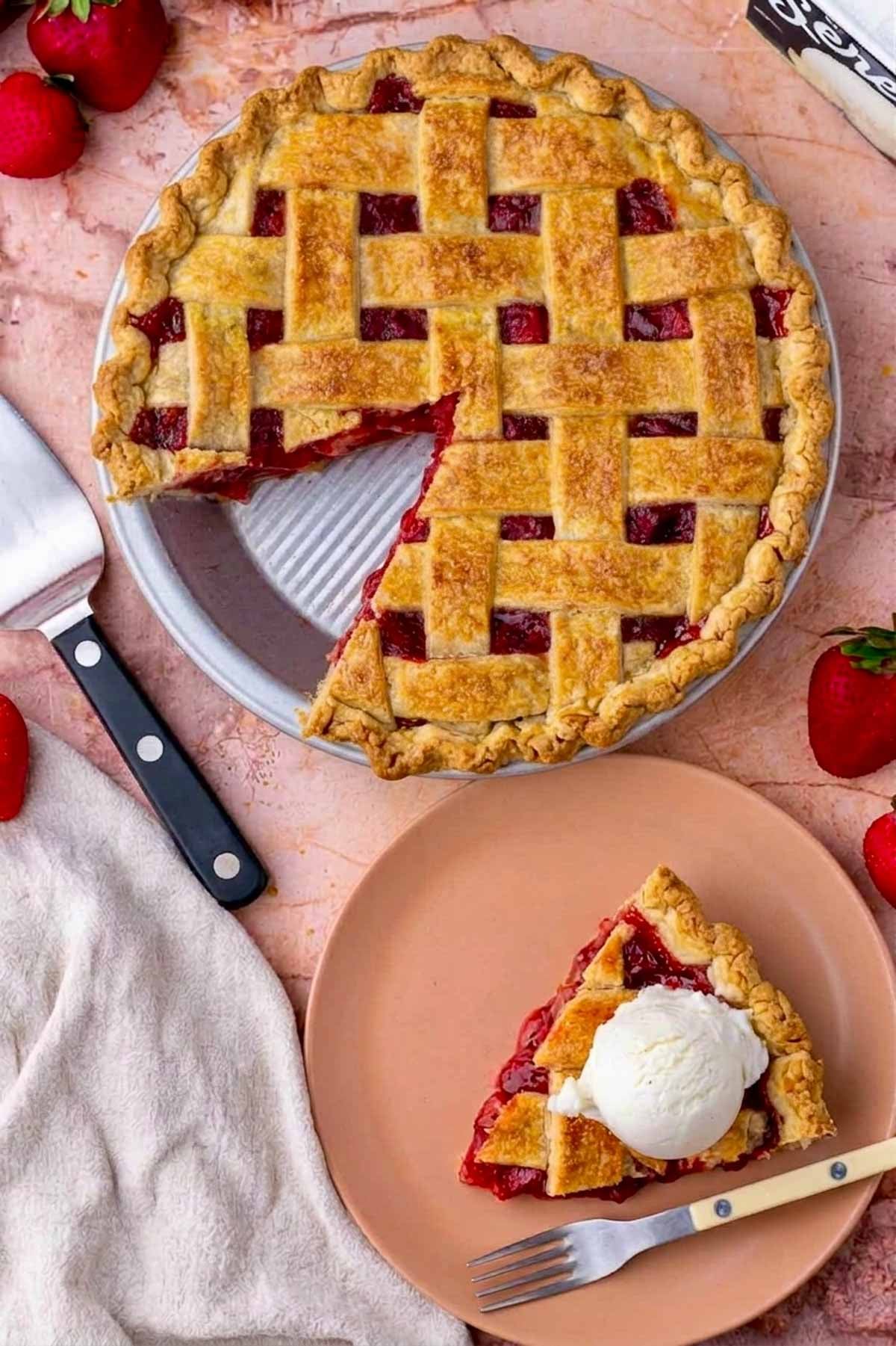 Sourdough strawberry rhubarb pie with a slice out of it and a slice of pie with a scoop of ice cream on a plate with a fork.