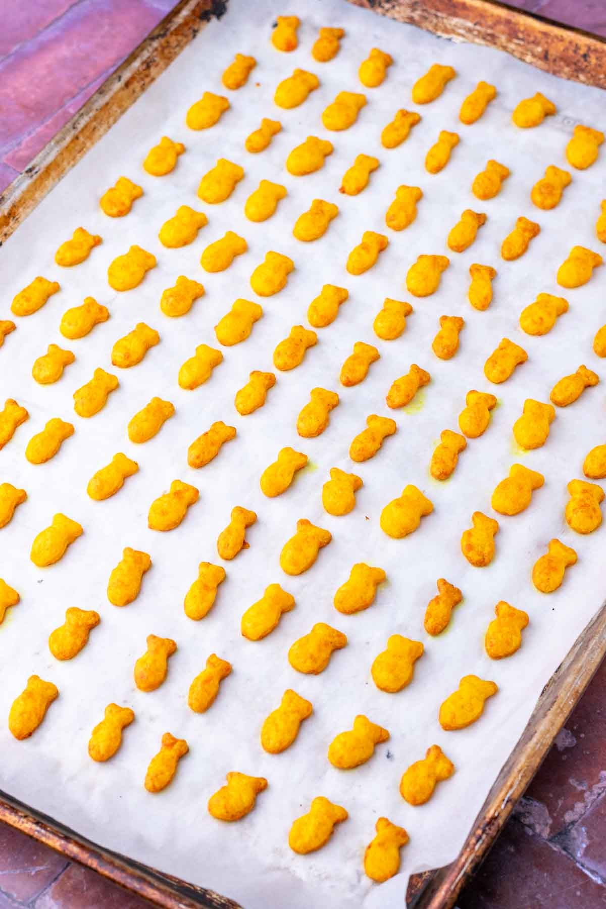 Baked sourdough goldfish on a large sheet pan with parchment paper.