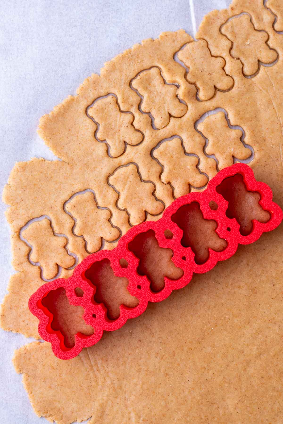 Cutting out sourdough teddy grahams with a bear cookie cutter.