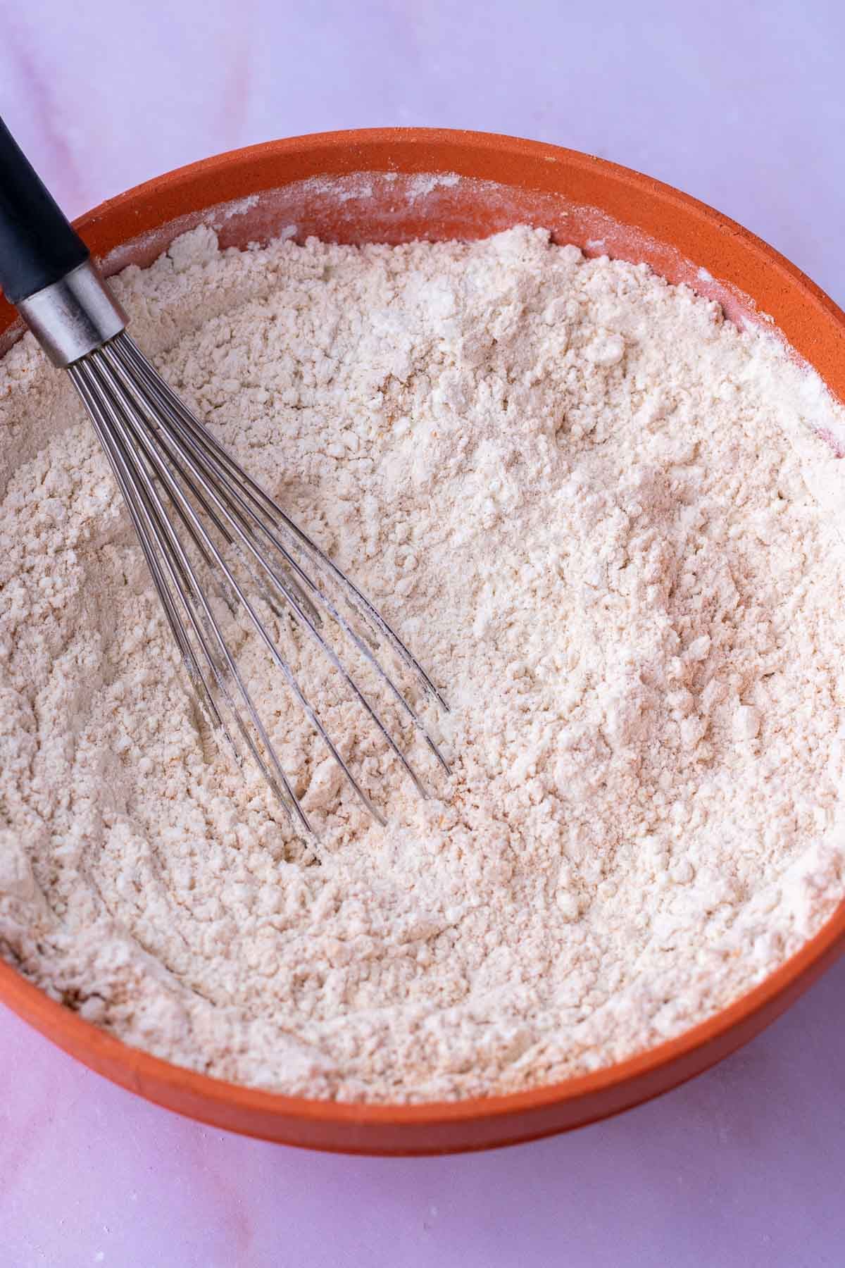 Whisk mixing dry ingredients in a bowl for sourdough animal crackers.