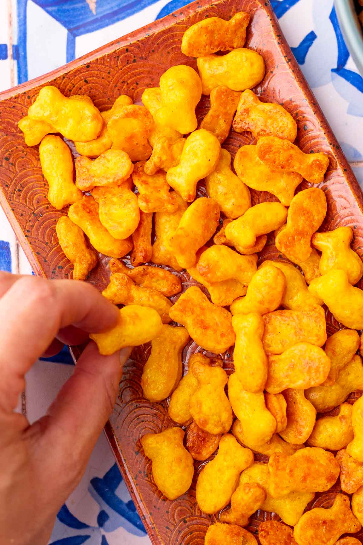 Hand picking up sourdough goldfish from a tray.