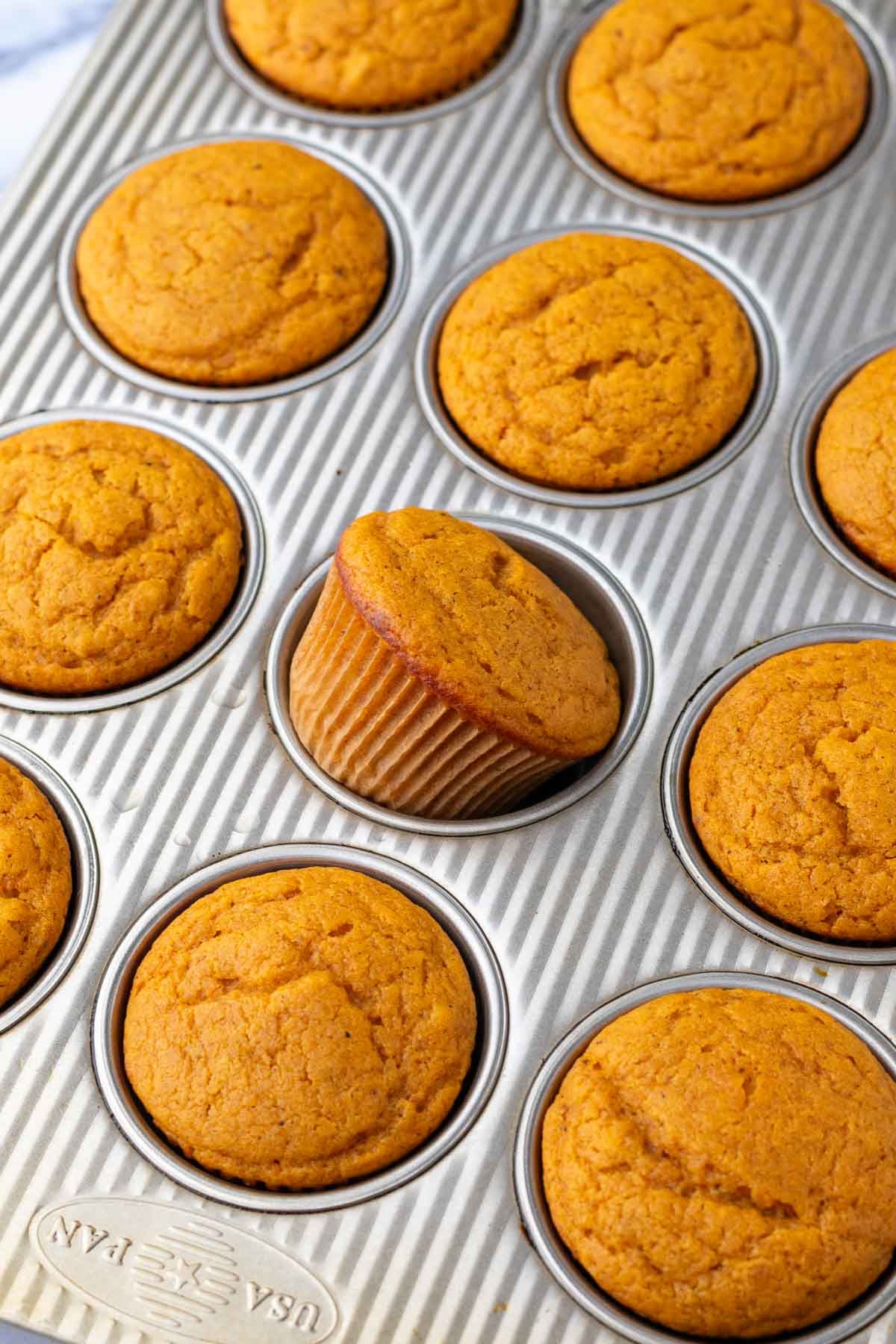 Baked sourdough pumpkin cupcakes in a muffin pan.