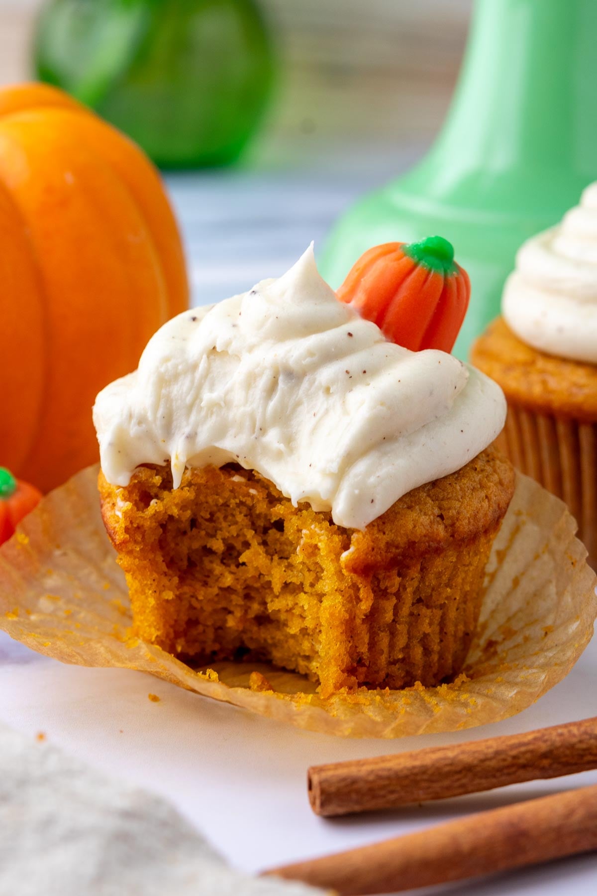 Bite taken out of a sourdough pumpkin cupcake with brown butter cream cheese frosting.