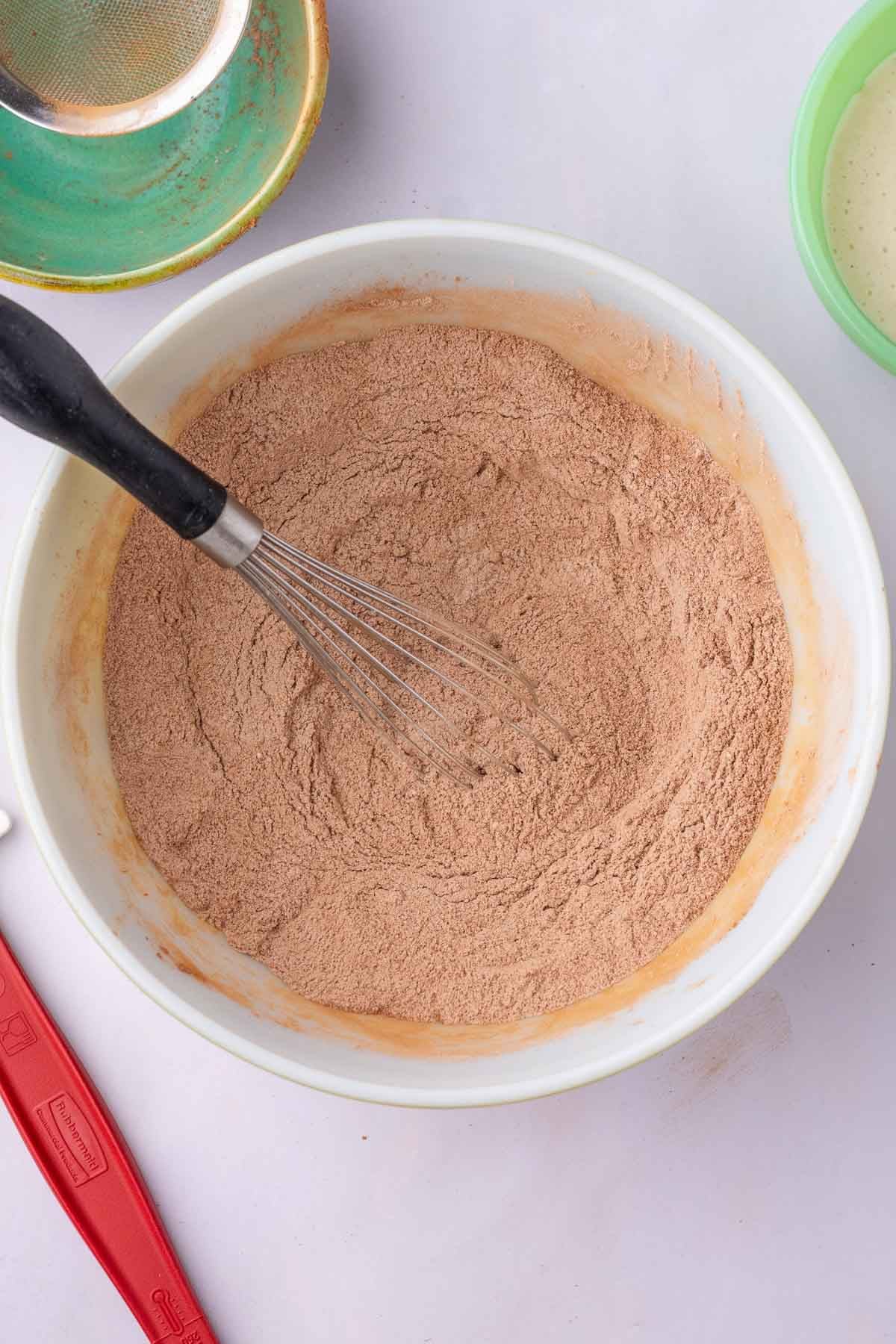 Bowl of mixed dry ingredients for sourdough cocoa puffs with a whisk.