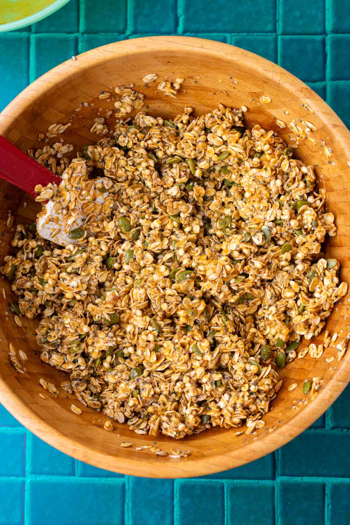 Mixed sourdough pumpkin granola in a large wooden bowl with a spatula.