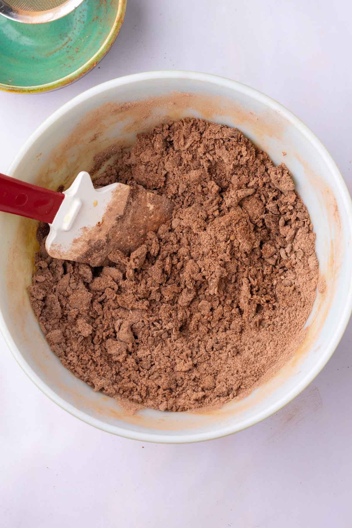 Spatula mixing sourdough cocoa puff dough in a bowl.