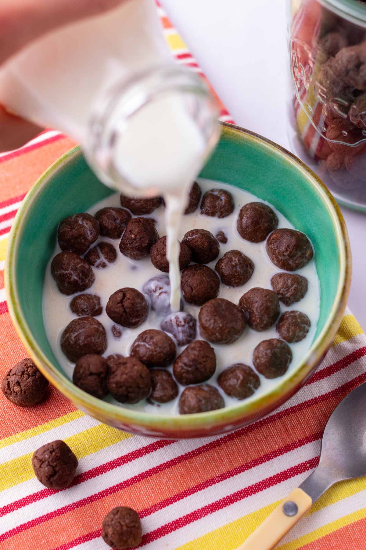 Pouring milk from a glass into a cereal bowl of sourdough cocoa puffs.