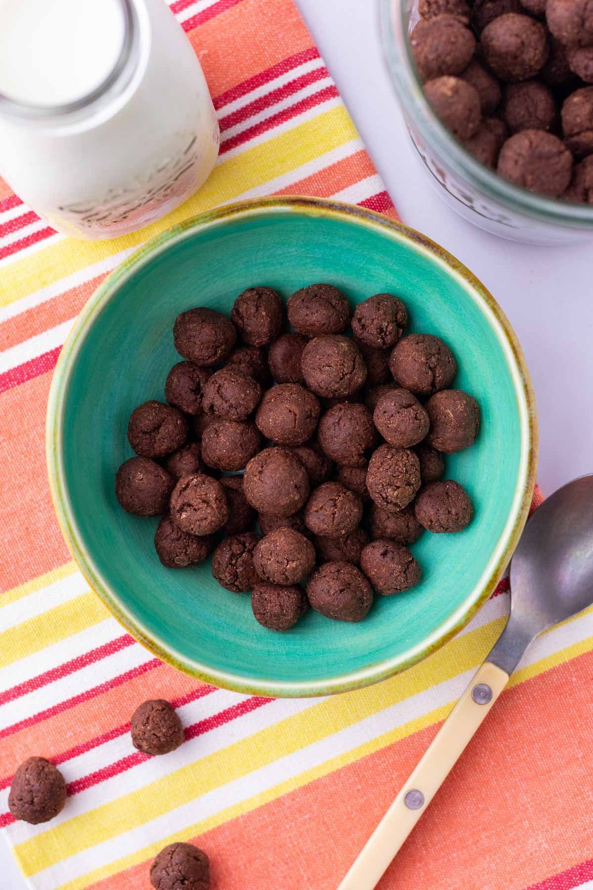 Bowl of sourdough cocoa puffs with a glass of milk and a spoon.