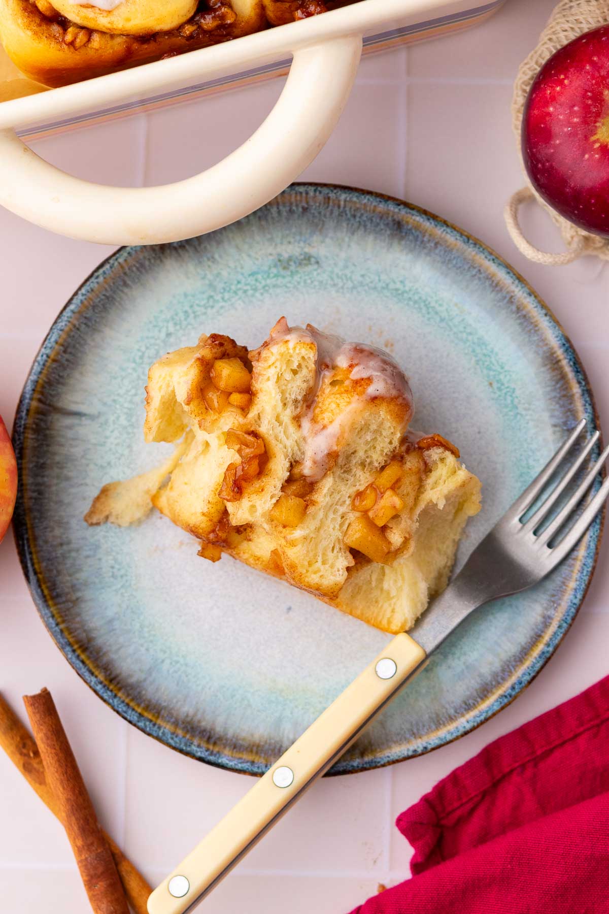 Bite taken out of a sourdough apple cinnamon roll on a plate with a fork.