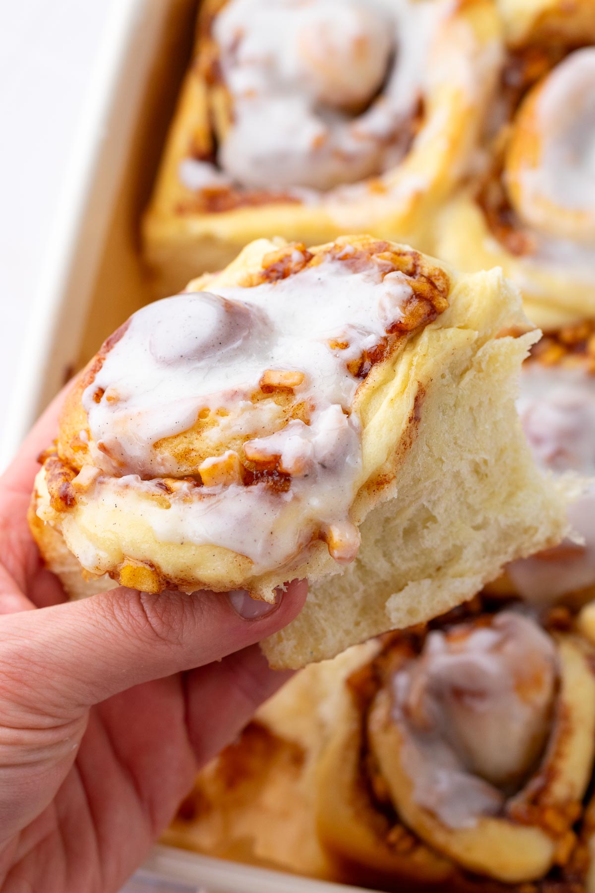 Hand holding a fluffy sourdough apple cinnamon roll.
