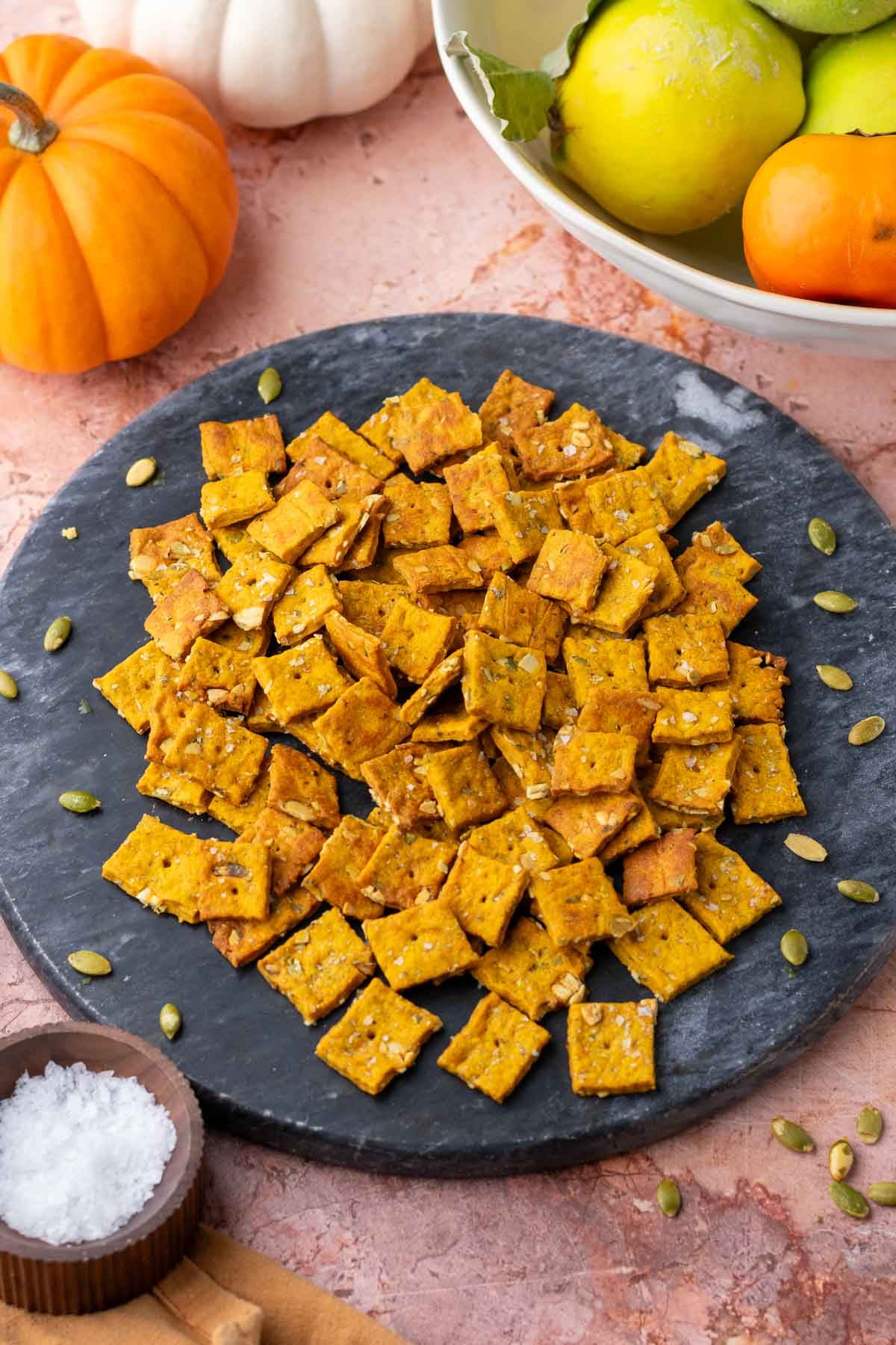 Platter of sourdough pumpkin crackers surrounded by pumpkins.