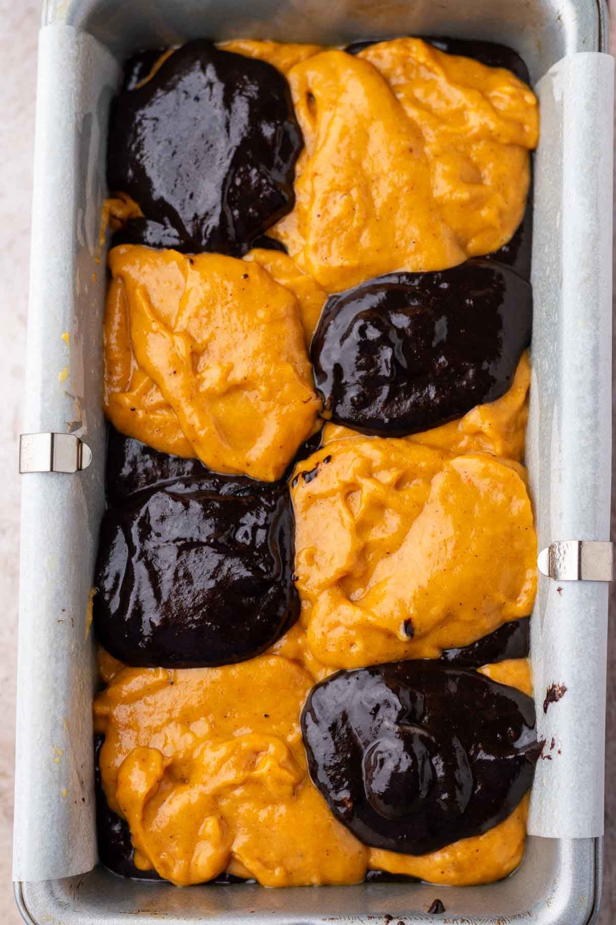 Pumpkin and black cocoa batters for sourdough pumpkin marble bread in loaf pan before swirling.