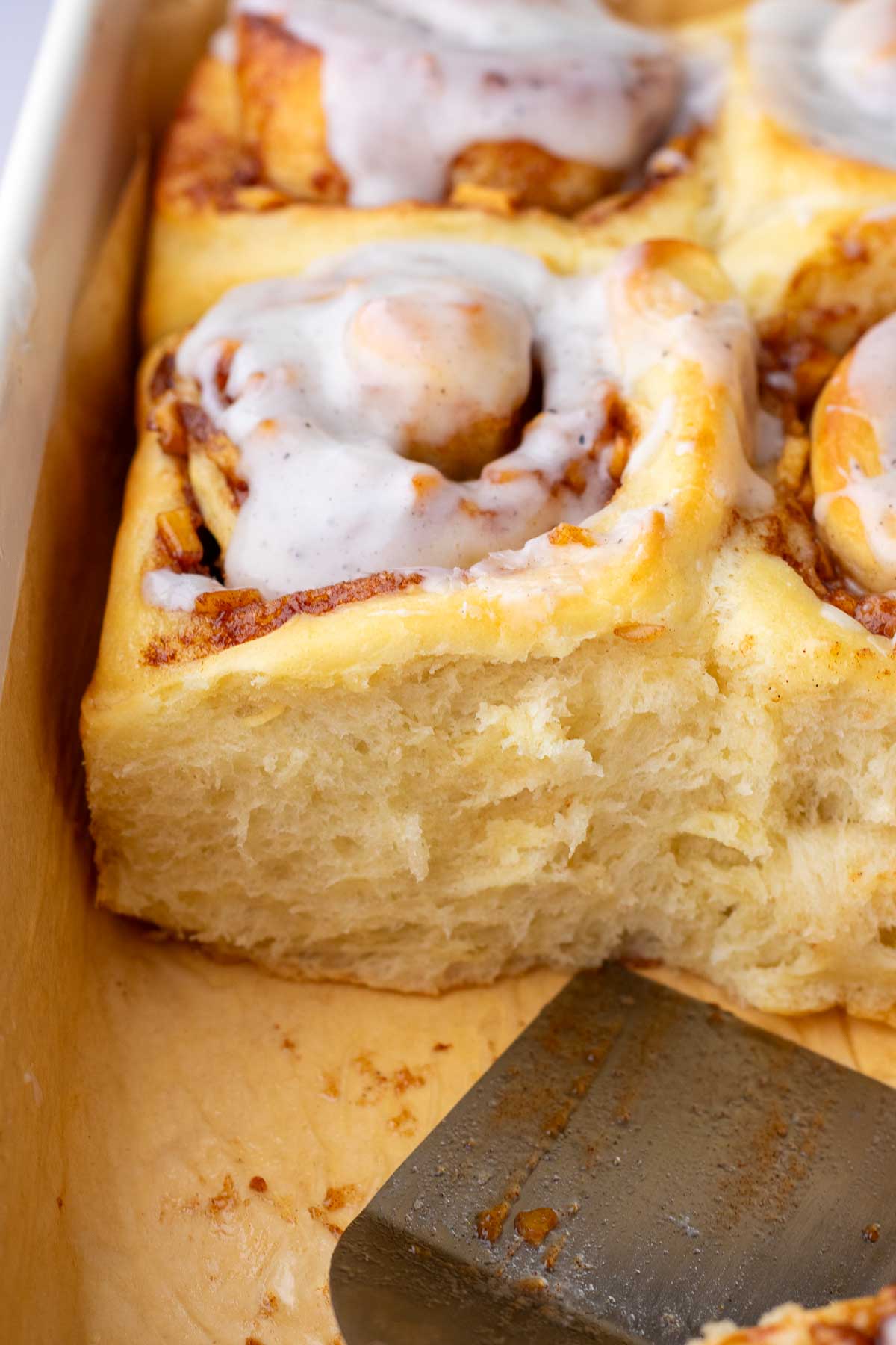 close up of a soft, baked sourdough apple cinnamon roll in pan.