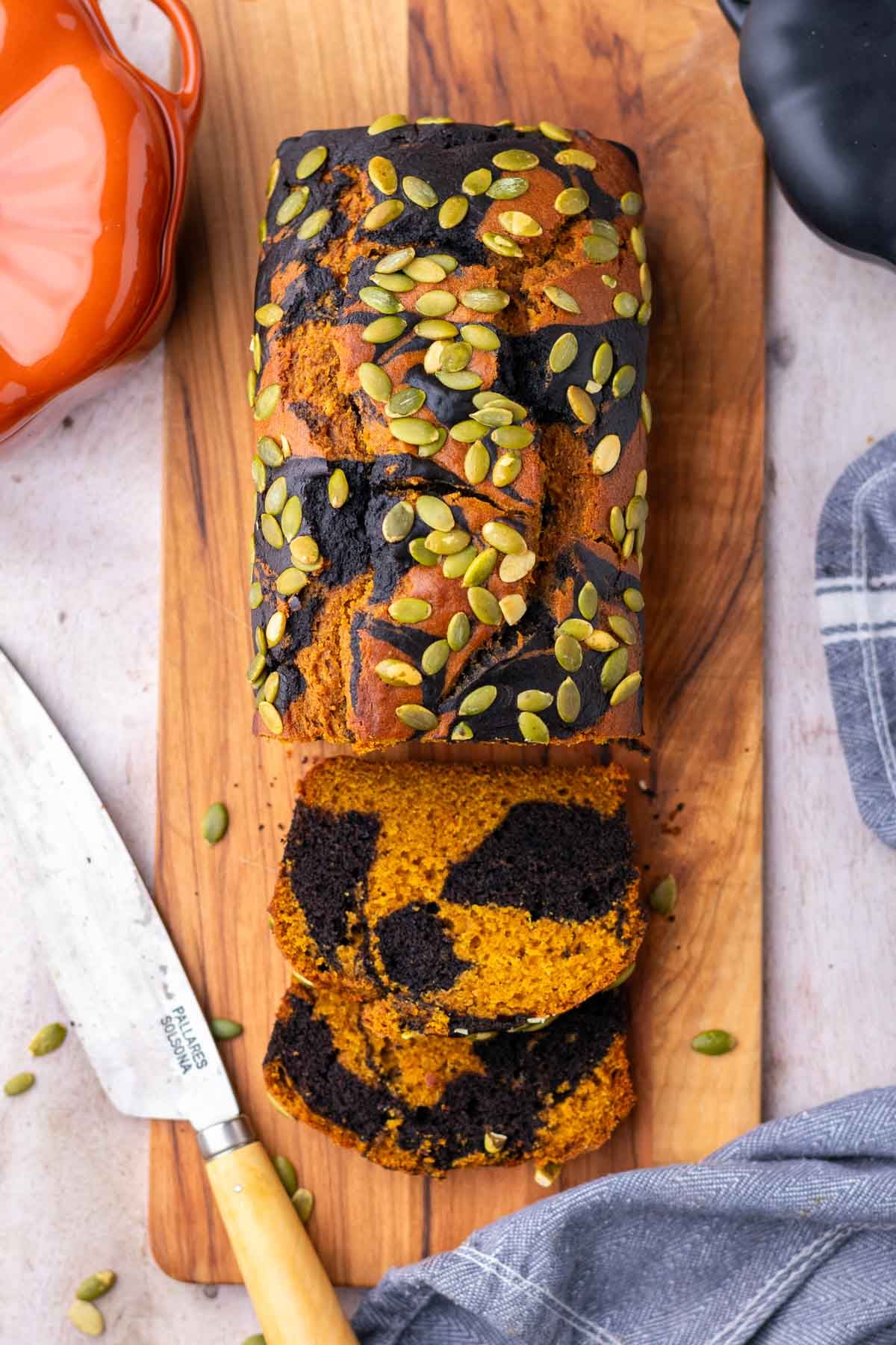 Sliced sourdough pumpkin marble bread on a cutting board with a knife.
