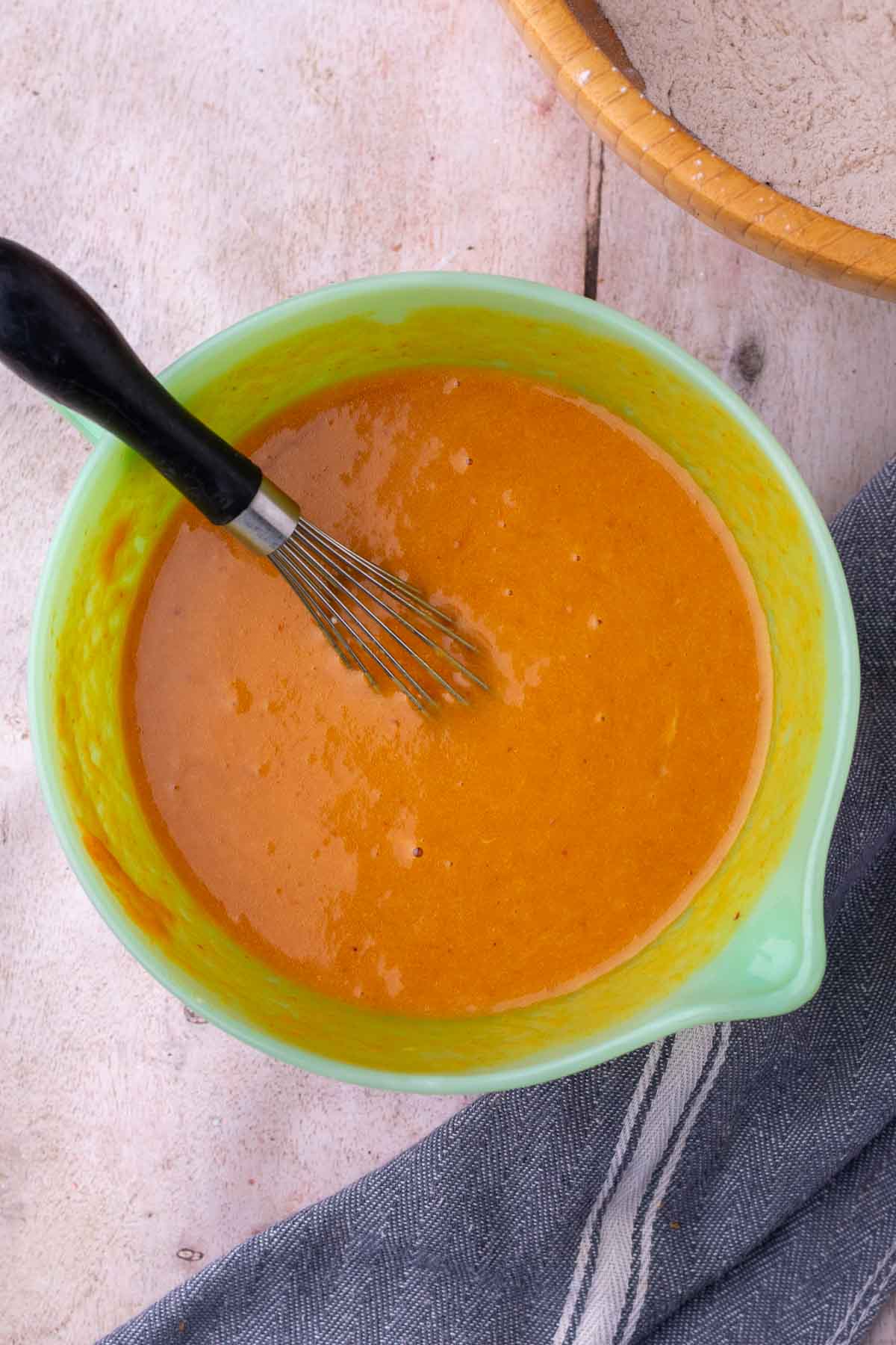 Bowl of mixed wet ingredients for sourdough pumpkin marble bread with a whisk.